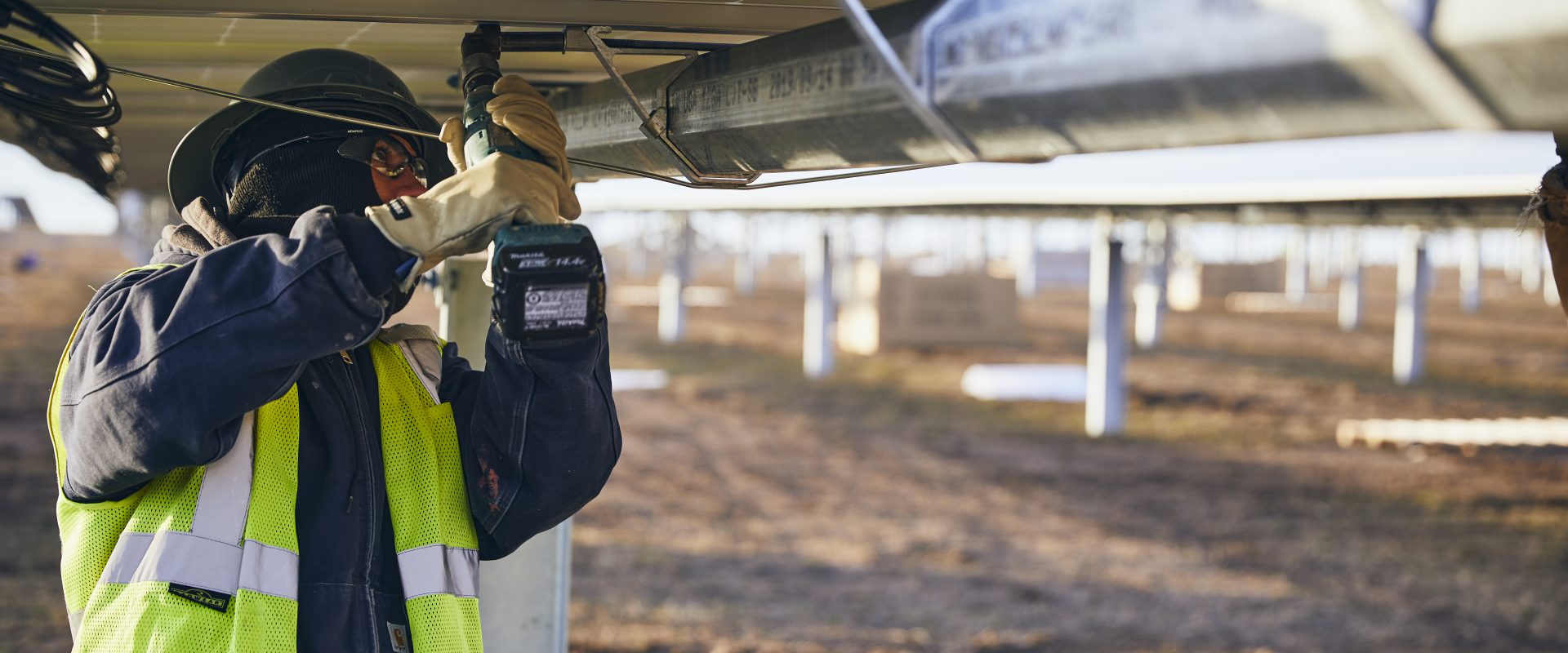 Worker working on solar panels in a field