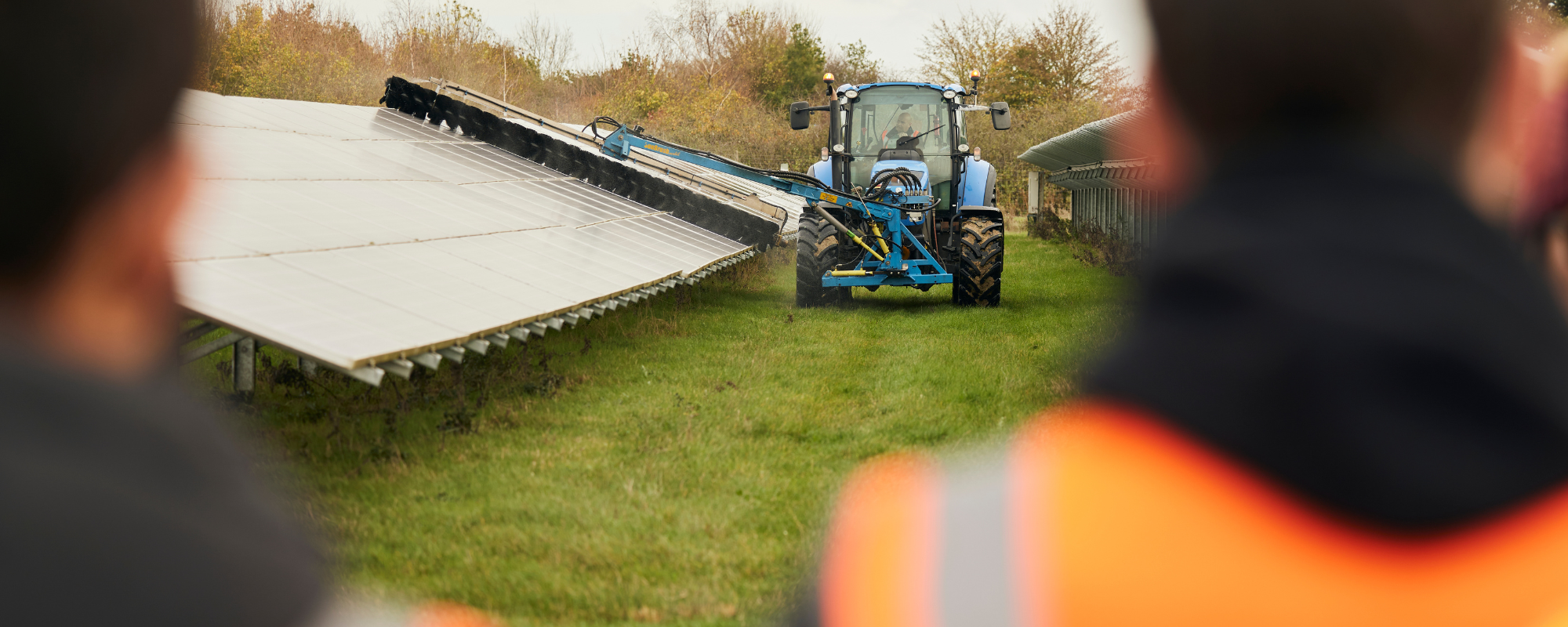 tractor working alongside solar panels