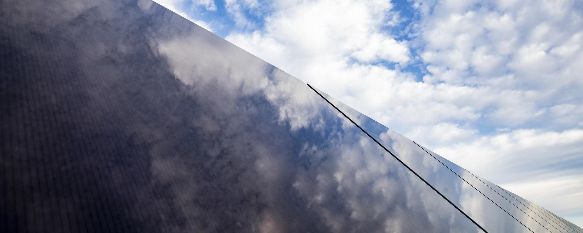 blue sky and clouds reflecting off a solar panel