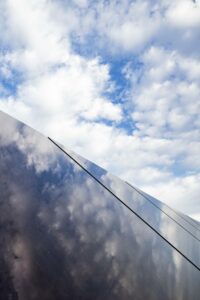 blue sky with clouds reflecting off a close up of a solar panel