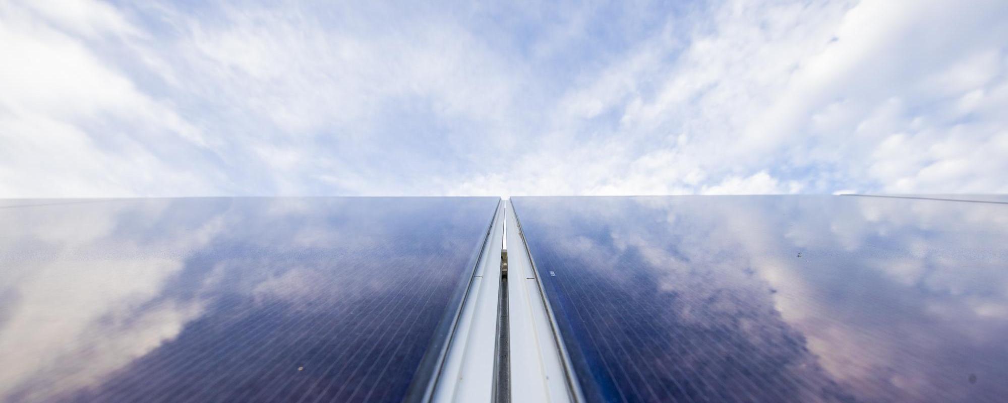 close up of solar panels with the sky reflecting off them