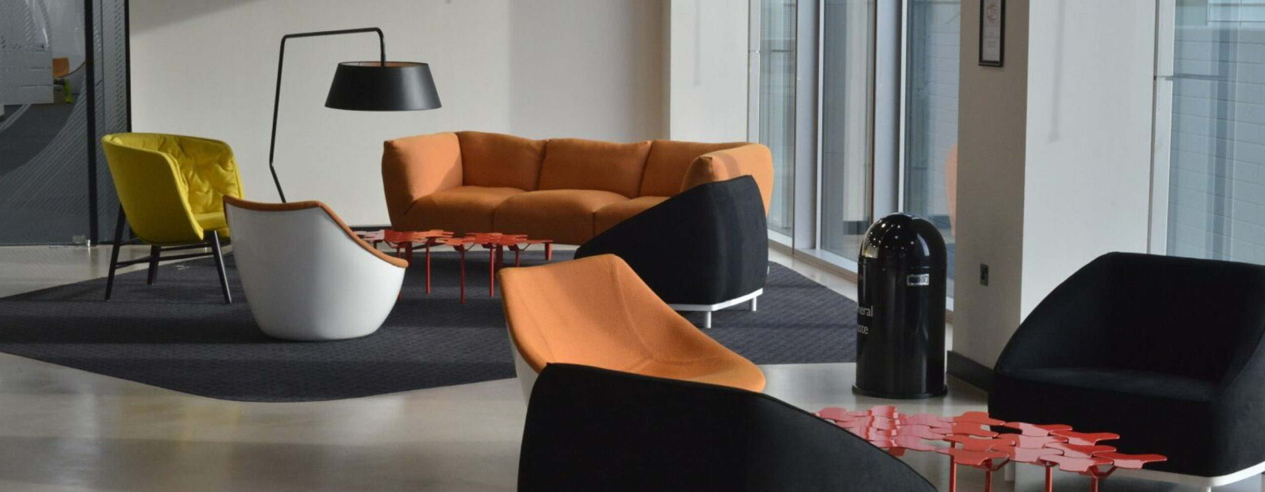 Photo of a modern office lounge area with comfortable seating, including armchairs, sofas, and coffee tables, creating a welcoming and collaborative workspace.