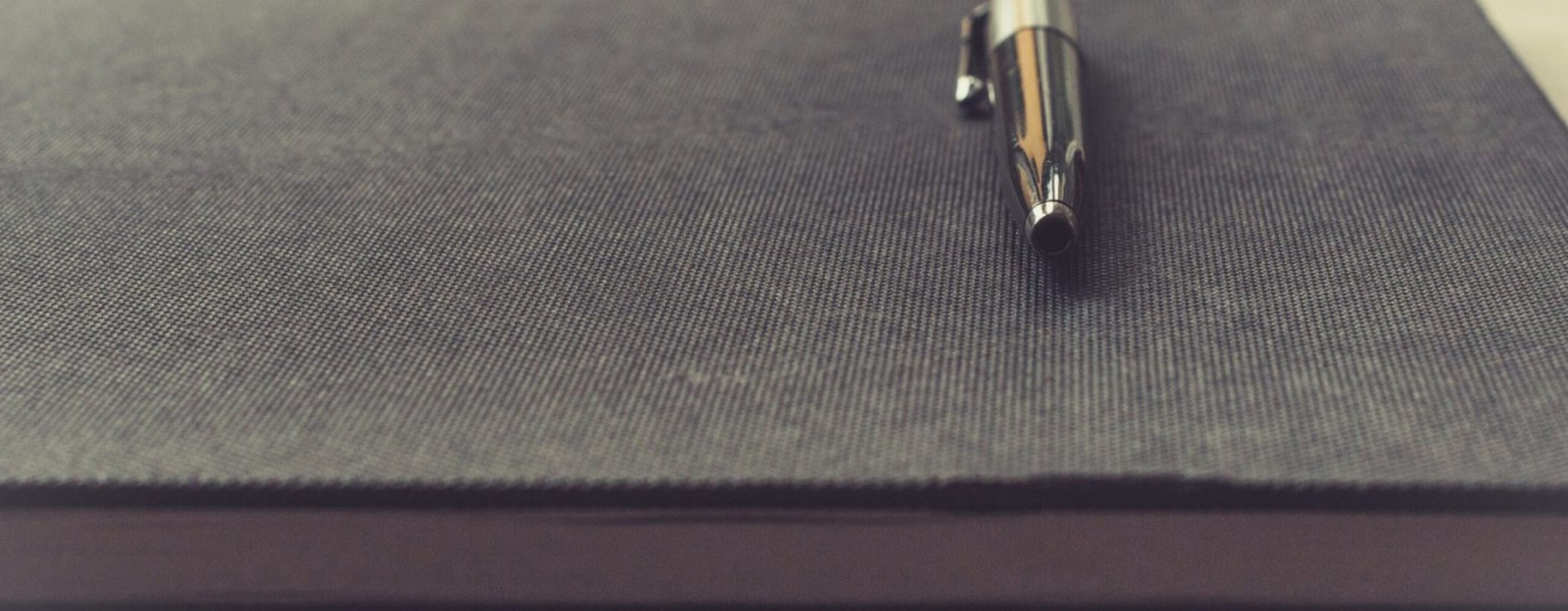 A silver pen resting on a gray notebook