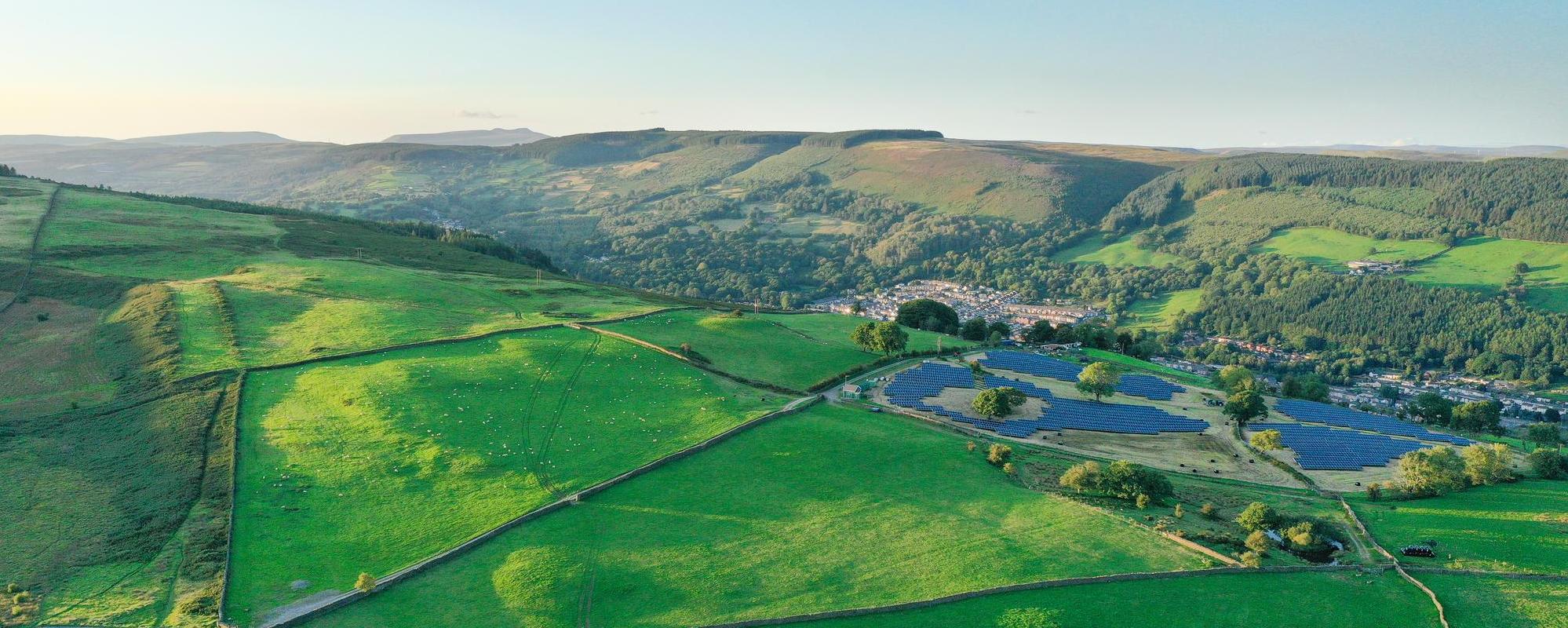 Aerial shot of a solar farm surrounded by green fields